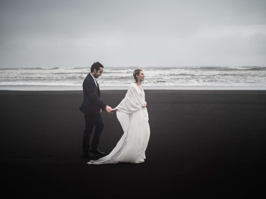 bride and groom walking alone on the black beach in ICeland