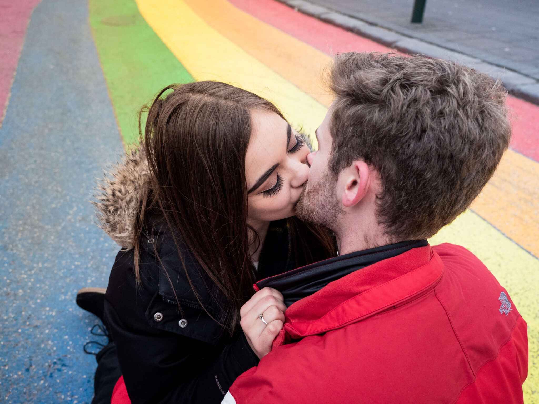 Engaged couple kissing on rainbow street in Reykjavik