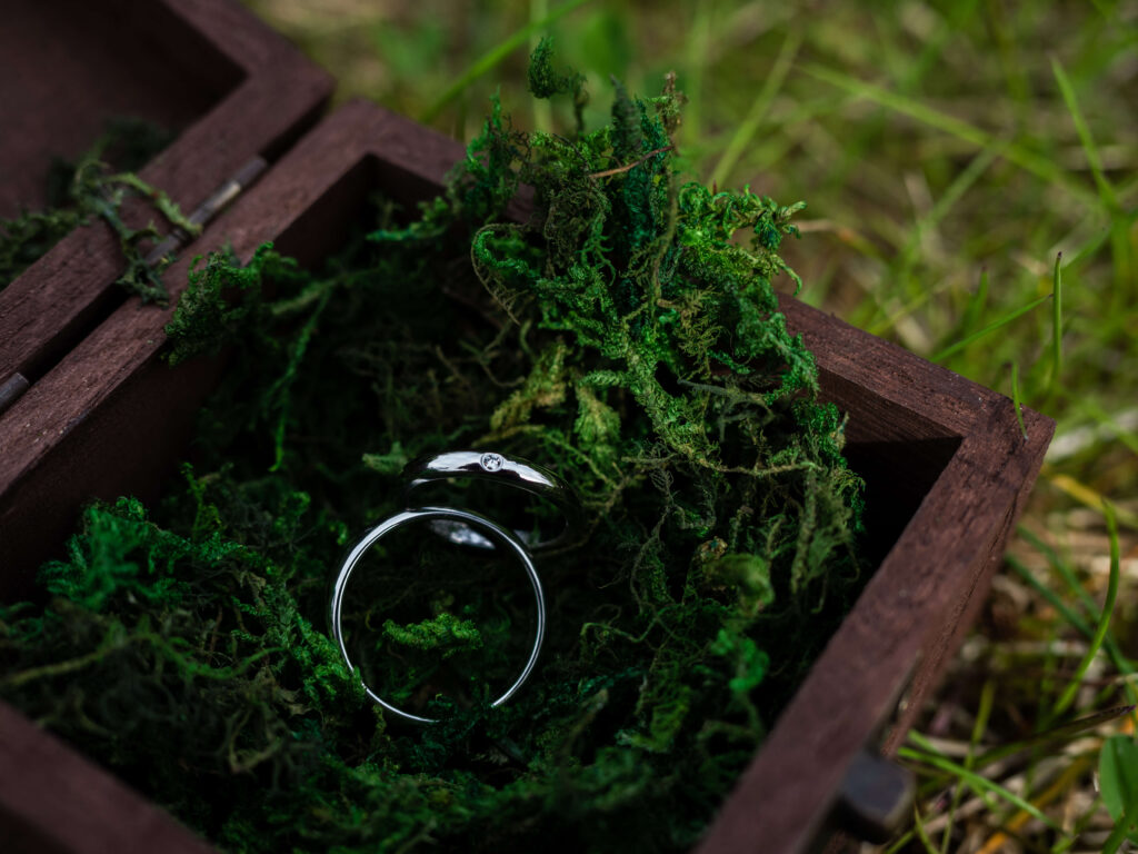 Wedding rings detail photo with wooden box and green moss