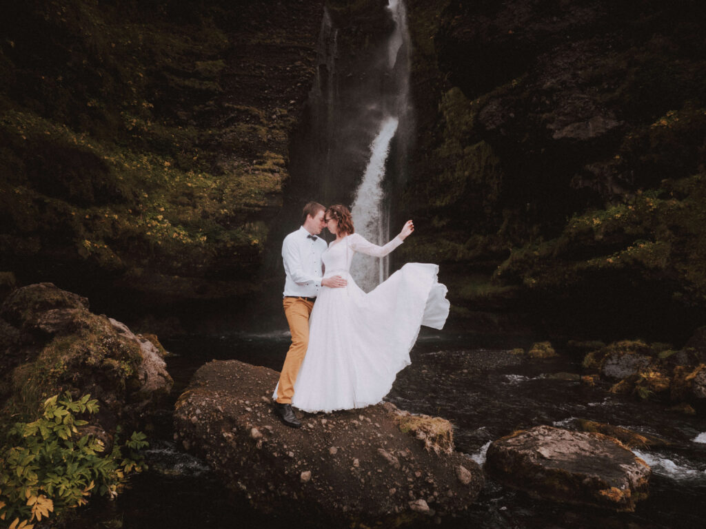 Bride and groom posin in Iceland with waterfall